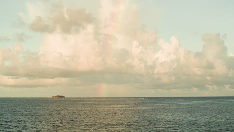 a view from siargao of a boat sailing by a rainbow and calm waters of the pacific ocean.