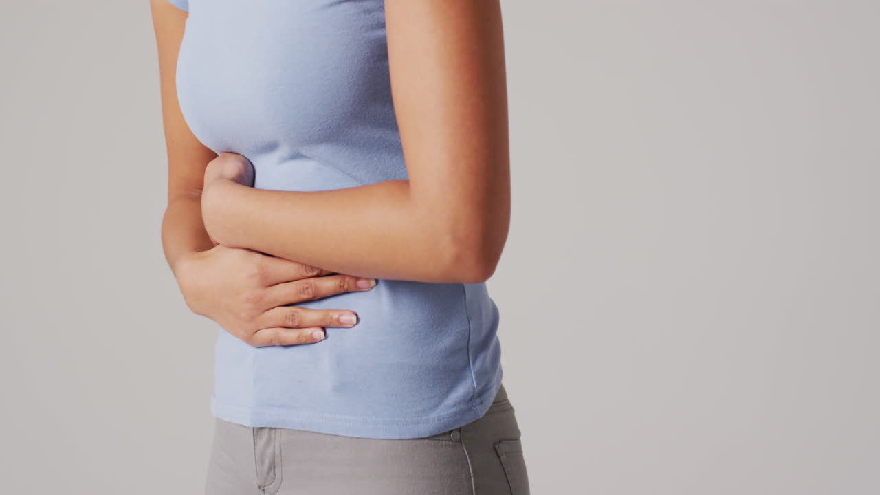 Video of biracial woman touching her stomach on white background