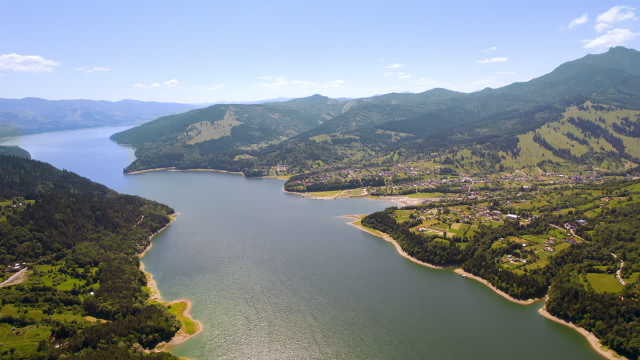 Vista aerea con drone della natura nei Carpazi in Romania al tramonto. Lago Izvorul Muntelui e un villaggio situato in una valle, colline ricoperte da una lussureggiante foresta