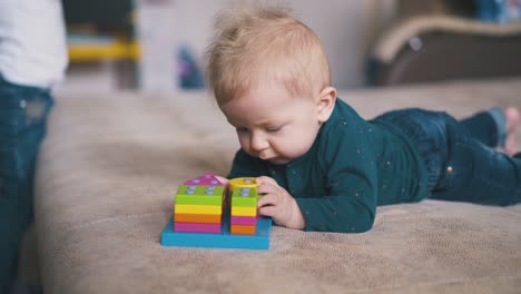 boy plays with colorful toy and sister with pyggybank on bed