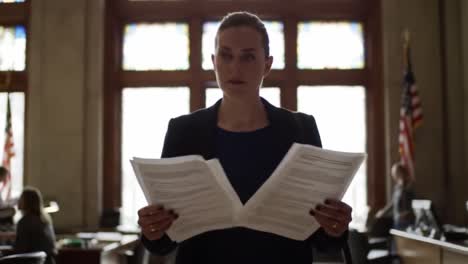 a woman stands in an elegant office, analyzing important documents. the large windows let in natural light, highlighting her focused expression as she prepares for a critical meeting.