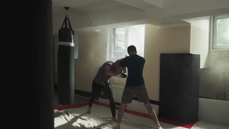 los boxeadores entrenan la reacción de ataque en el sparring en el gimnasio. la pareja de atletas se golpean fuertemente en el club deportivo en cámara lenta. técnicas de lucha de kickboxing