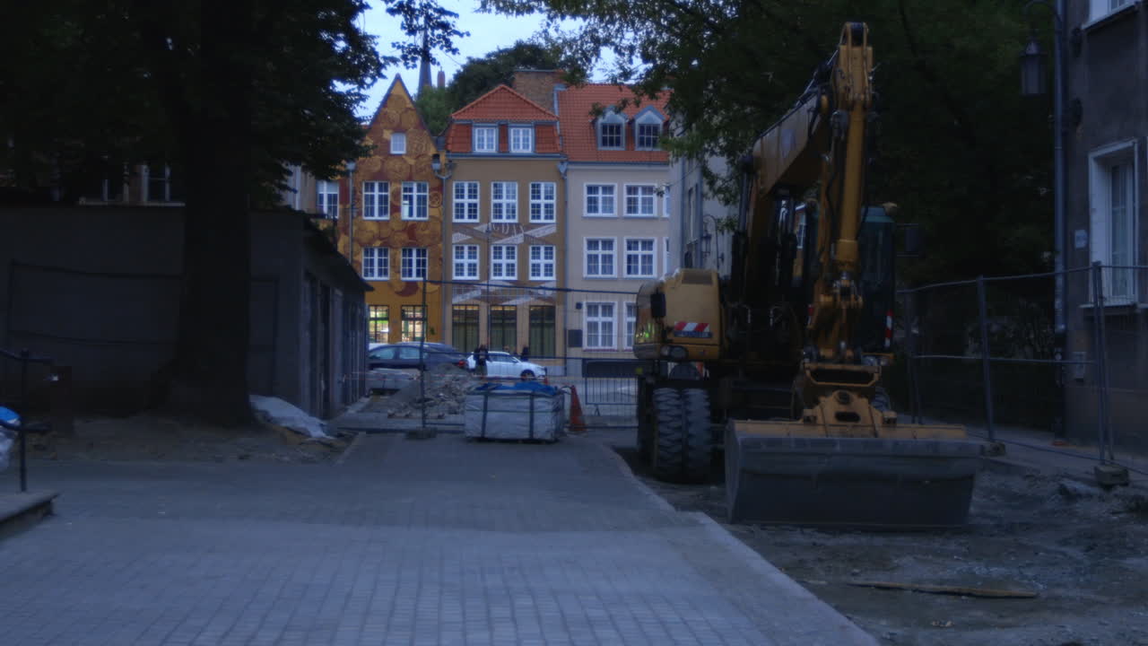renovación de la acera en la ciudad de gdansk, polonia, excavadora amarilla en el frente y típicos edificios tradicionales polacos en el fondo