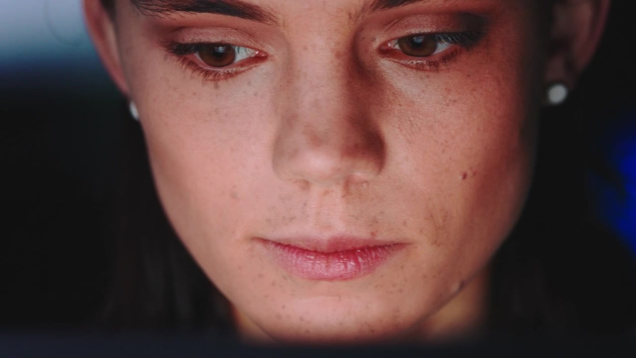 Primo piano di una giovane donna concentrata sullo schermo del computer di notte