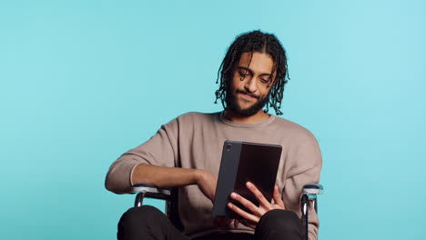 Man in wheelchair chatting with friend over internet videocall using tablet