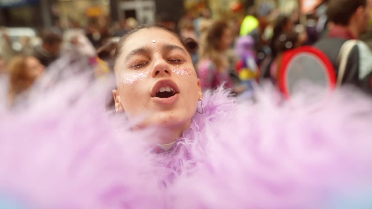 Giovane donna allegra con trucco glitterato e boa viola a un evento festivo