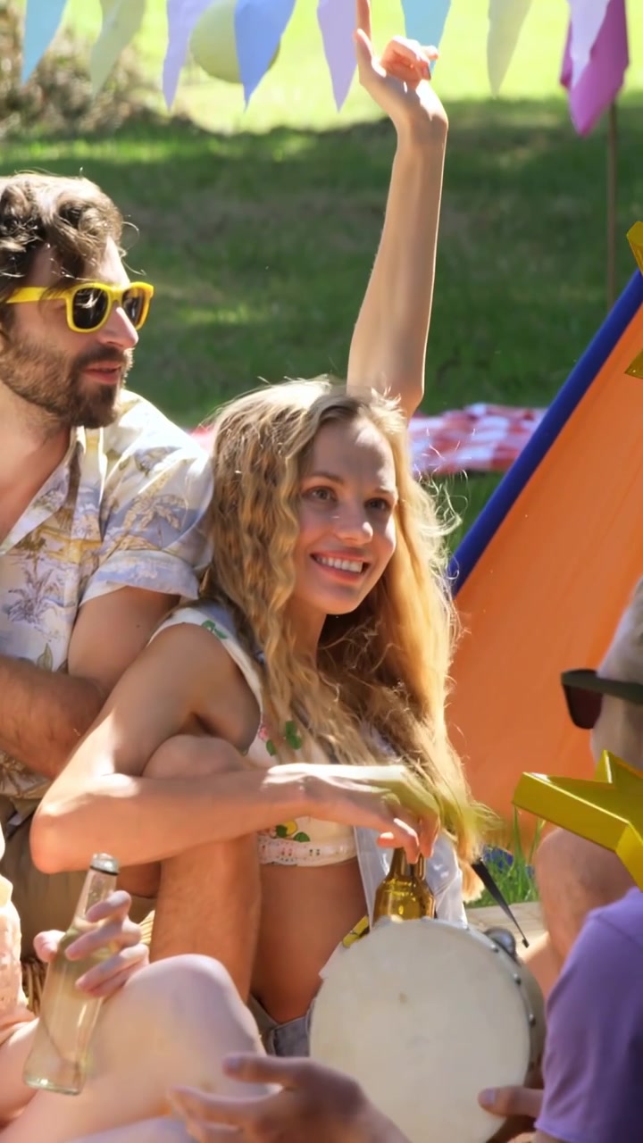 Video verticale: Donna avvia una chat al parco, tiene una bevanda, con stelle scintillanti che fluttuano sui volti, promo