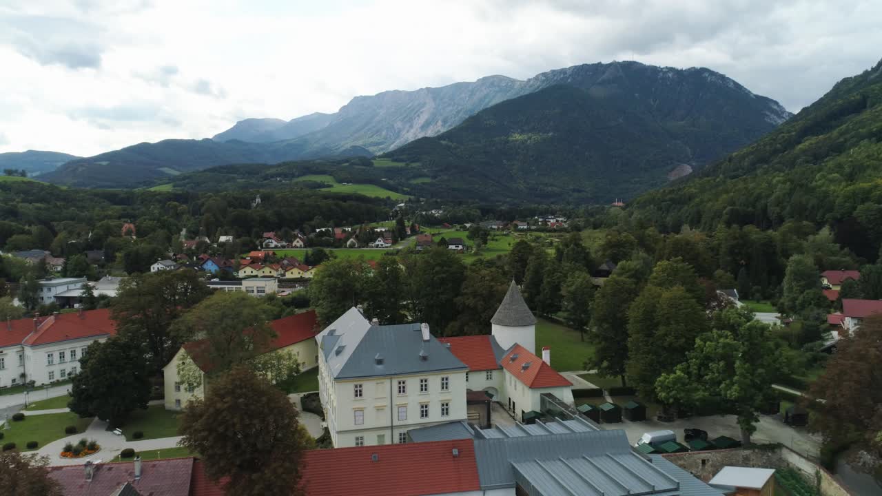 Ripresa con drone di un'antica e imponente villa davanti a montagne maestose.