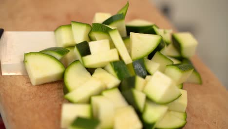 el cocinero vierte calabacines picados de la tabla de madera cortada con un cuchillo, prepara la ensalada de verduras, cocina con verduras, vitaminas y alimentos saludables, comidas vegetarianas