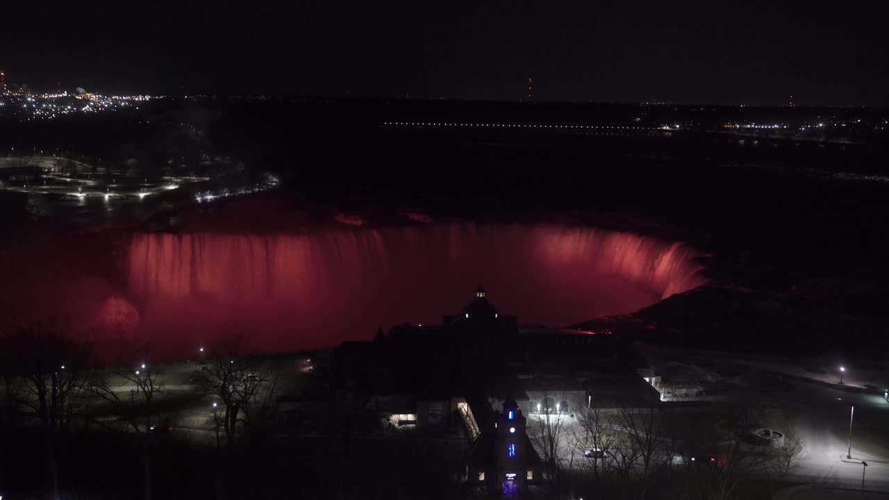 4k Niagara Falls lights glowing at night with flowing waterfalls; aerial view