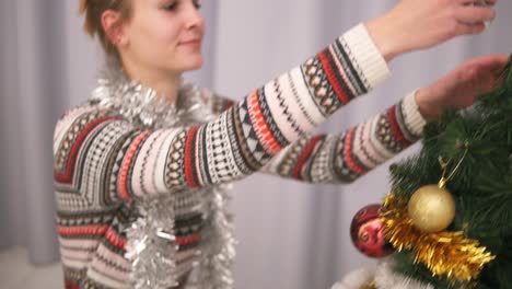 young happy woman decorating a christmas tree taking a silver star and hanging it on the top of the tree. slow motion shot