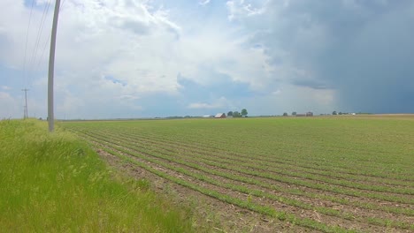 Langsamer-Schwenk-über-Ein-Feld-Mit-Großen-Aufziehenden-Gewitterwolken-In-Der-Ferne