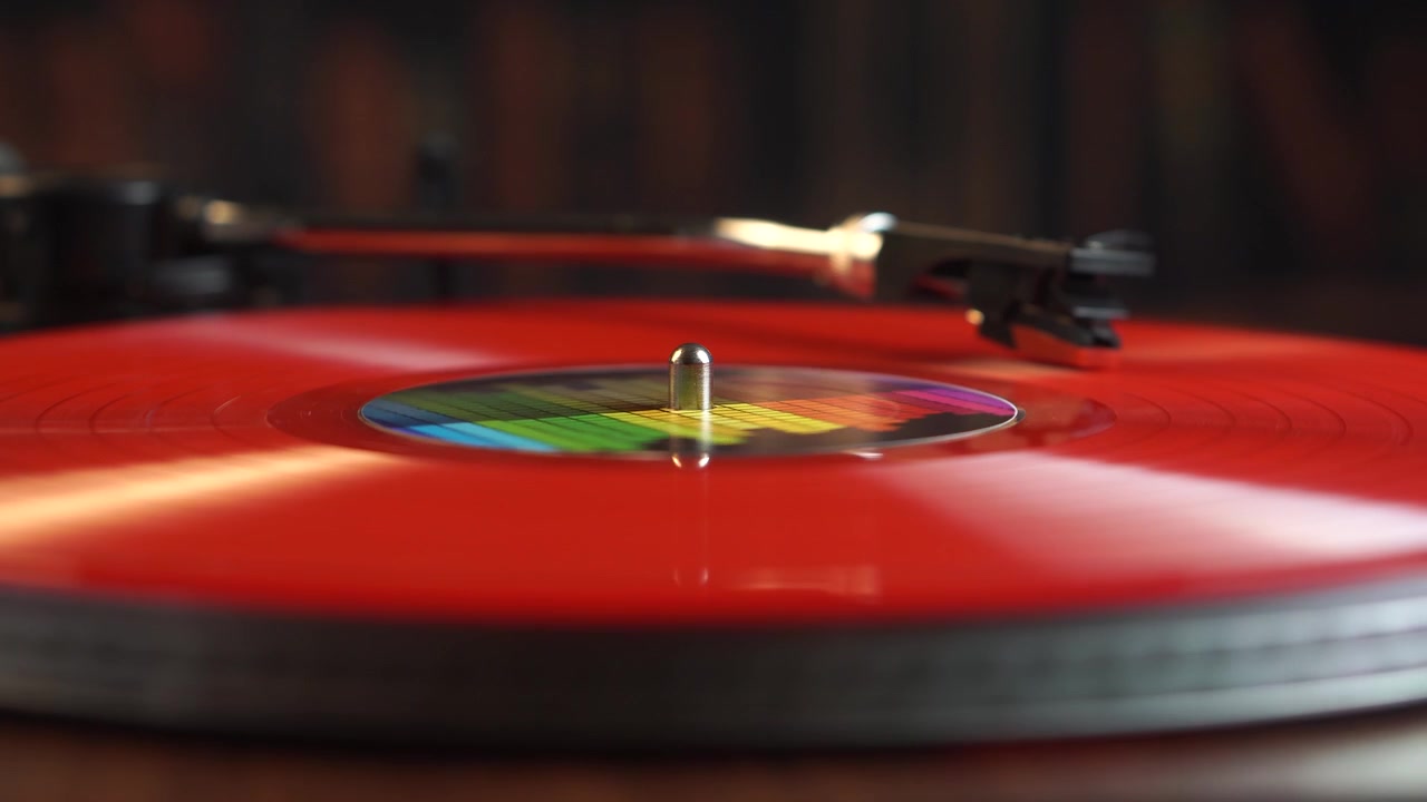 Puntina su disco in vinile rosso che gira su giradischi vintage, primo piano.