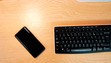 smartphone and keyboard on wooden desk