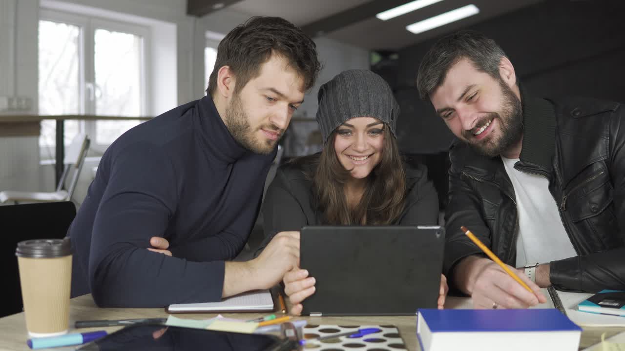 equipo de jóvenes profesionales teniendo una reunión en una oficina creativa. mirando la pantalla de una tableta y tomando fotos. filmado en 4k
