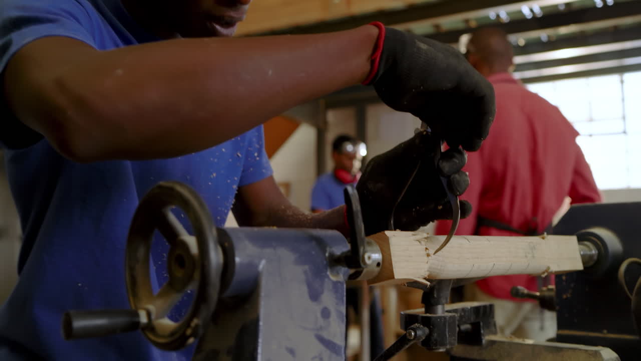 African American instructor mounting blank on lathe, guiding apprentice shaping wood in workshop