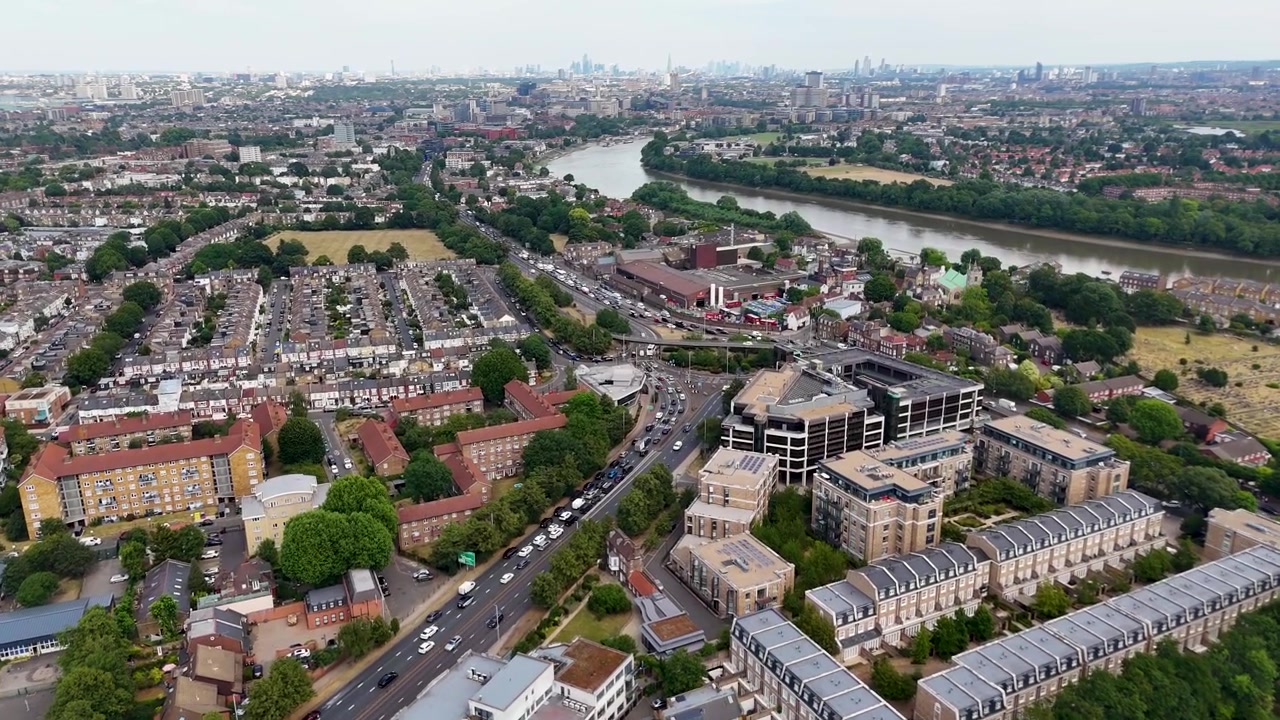 Ampia vista su un sobborgo di Londra ovest con la sua strada principale, l'ansa del fiume e le torri distanti della città all'orizzonte