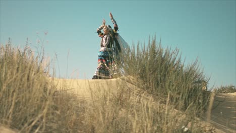 mujer gitana bailando y agitando sus manos en el desierto