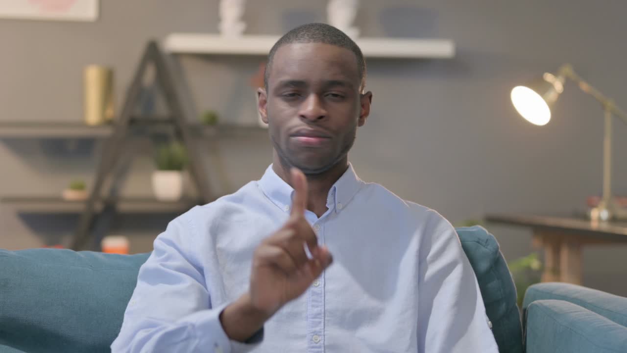 African Man Showing NO Sign while Sitting on Sofa