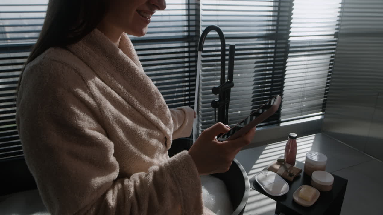 Woman relaxing in a bubble bath using a smartphone