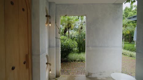 walking through an outdoor washroom at a resort in antigua into a lush, green landscaped area with light rain falling