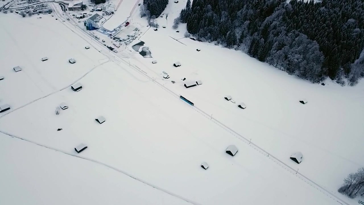 Ripresa aerea che segue un treno che attraversa la città di Grainau in un inverno nevoso. Baviera, Germania