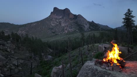 male camper stokes campfire atop boulder in san isabel national forest, drone