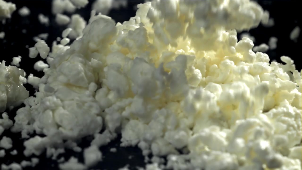 Fiocchi di latte freschi che cadono al rallentatore su uno sfondo nero.