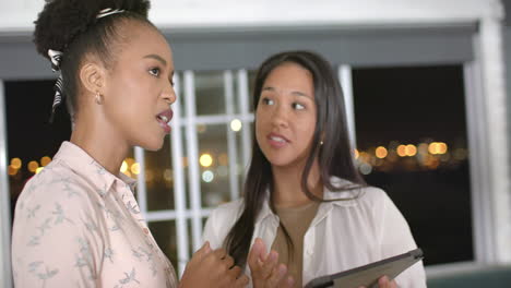 Young-African-American-woman-converses-with-biracial-woman-in-a-business-office-setting