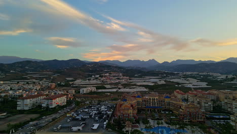 Establishment-aerial-shot-of-the-beautiful-spanish-city-of-malage-overlooking-the-historic-buildings-during-dusk-at-golden-hour-with-mountains-in-the-background