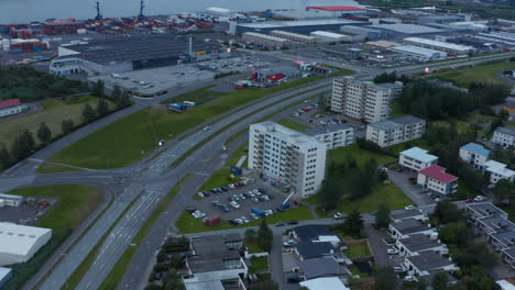 Fly-above-town,-wide-multilane-road-dividing-residential-borough-and-logistic-area-with-harbour.-Reykjavik,-Iceland