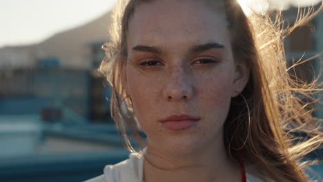 portrait-redhead-woman-with-freckles-looking-serious-with-wind-blowing-hair-teenage-girl-in-city-at-sunset-self-image-testimonial-concept