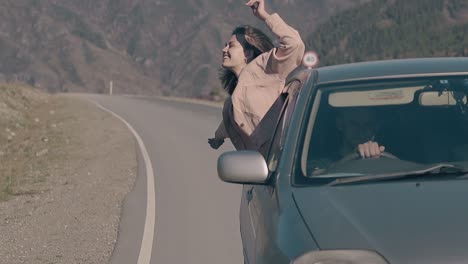 una dama de cabello corto se inclina hacia fuera del coche y siente felicidad