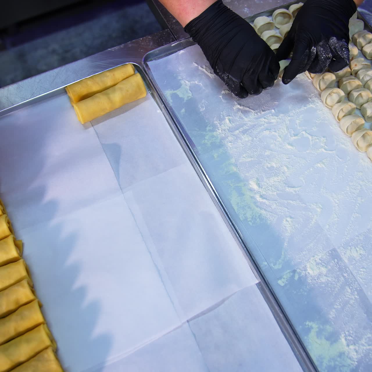 Chefs lay the ready-made food on the metal trays. Semi -cooked ravioli and stuffed crepes gathered together. Top view