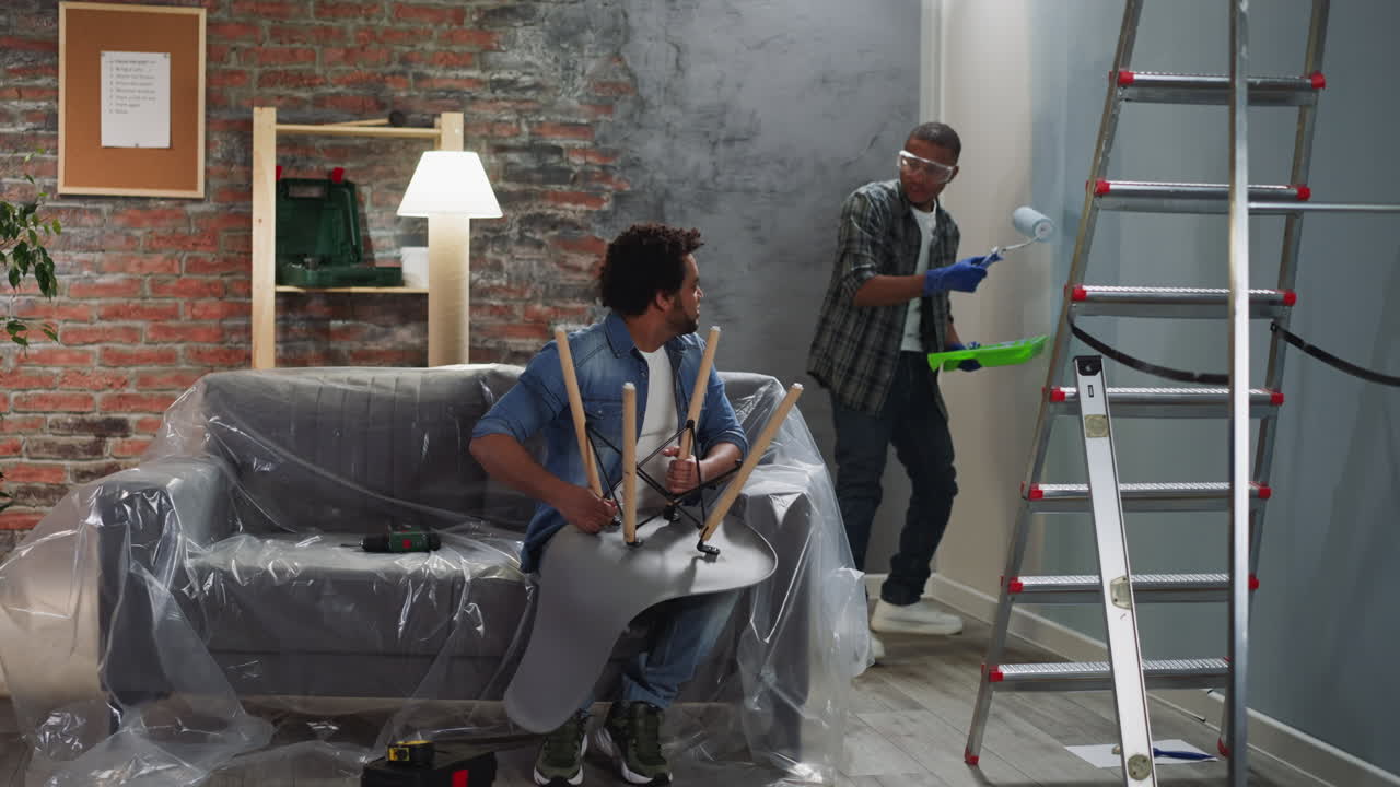 아프리카계 미국인 남자가 벽을 칠하고 형제의 시선을 요청합니다.