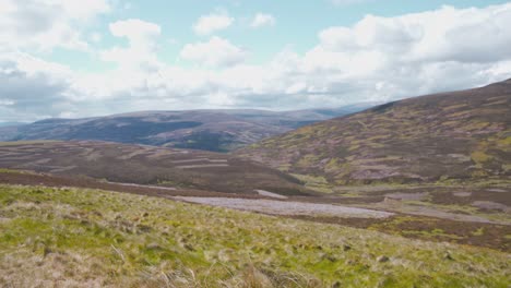 Scenic-view-of-treeless-scottish-highland-and-hills-under-white-clouds