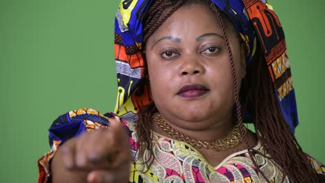 overweight beautiful african woman wearing traditional clothing against green background