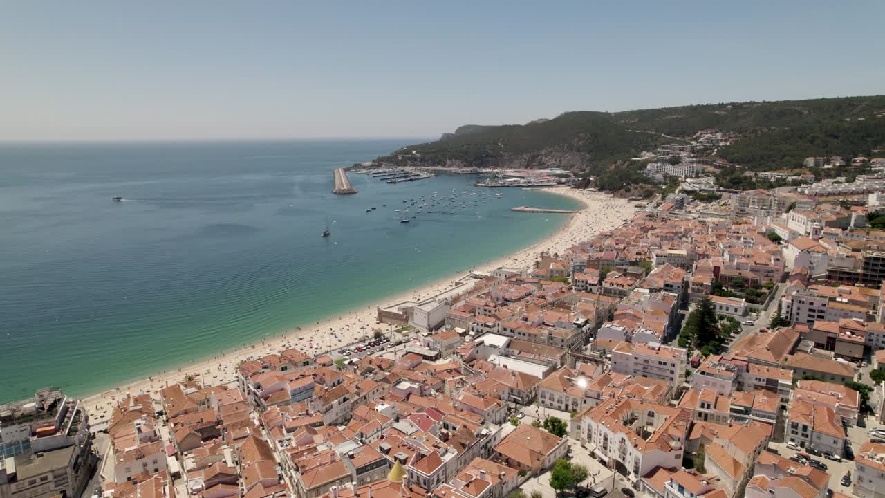 Sesimbra, vista aerea della spiaggia e del paesaggio urbano sullo sfondo del porto turistico e delle colline.