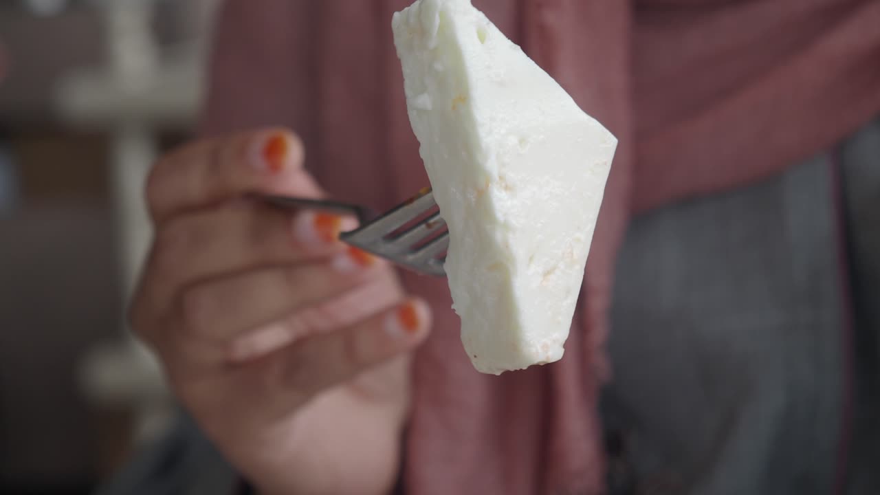 mujer sosteniendo un pedazo de queso en un tenedor