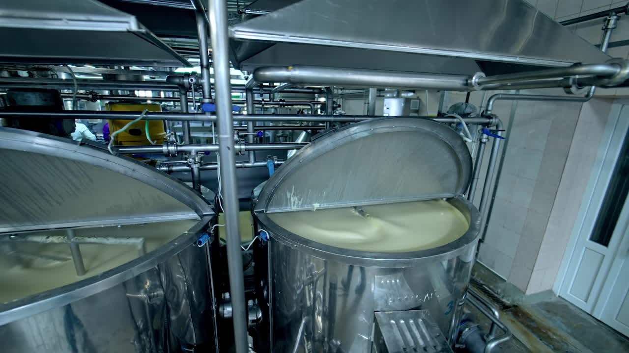 Three silver tanks for mixing milk products. Dairy production at the modern food factory. Steel tanks with open lids standing in row.