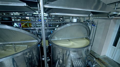 three silver tanks for mixing milk products. dairy production at the modern food factory. steel tanks with open lids standing in row.