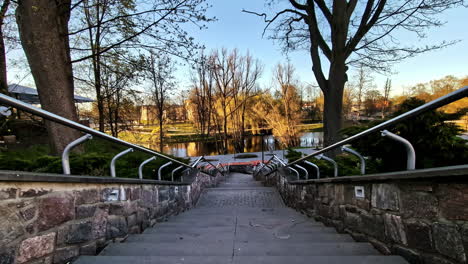 stone staircase with metal railing leading to park pond in valmiera, latvia