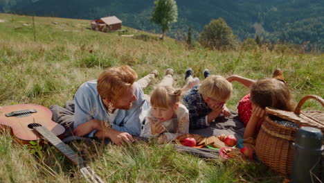 parents enjoy picnic children lying grass mountain slope. family resting outdoor