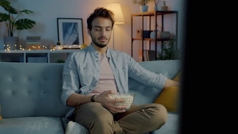hombre viendo la tv con palomitas de maíz