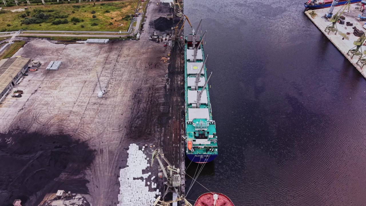 Grande nave da carico carica materiali in un porto di giorno con macchinari