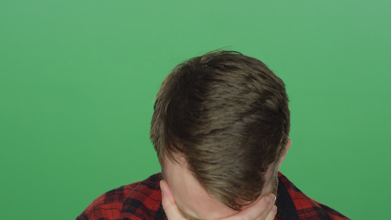 녹색 스크린 스튜디오 배경에서 슬프게 보이는 젊은 수염이 있는 남자
