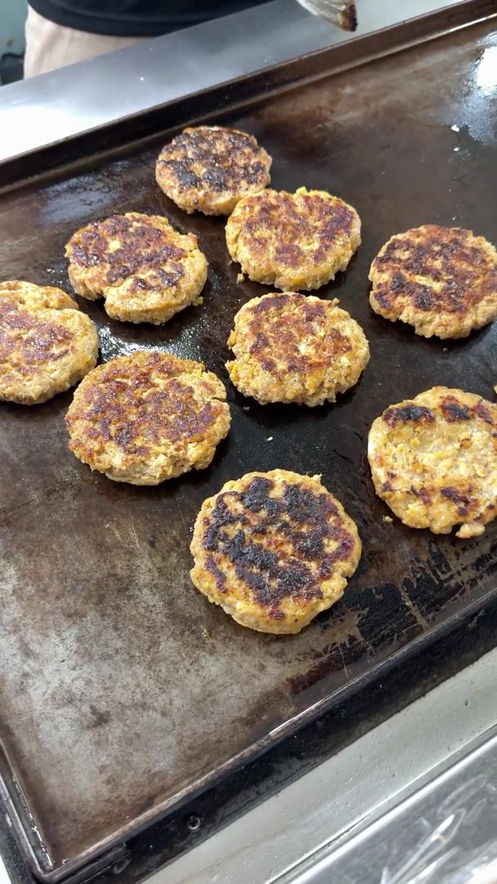 Chef Grilling Fresh Meat Patties on a Commercial Flat Top Grill