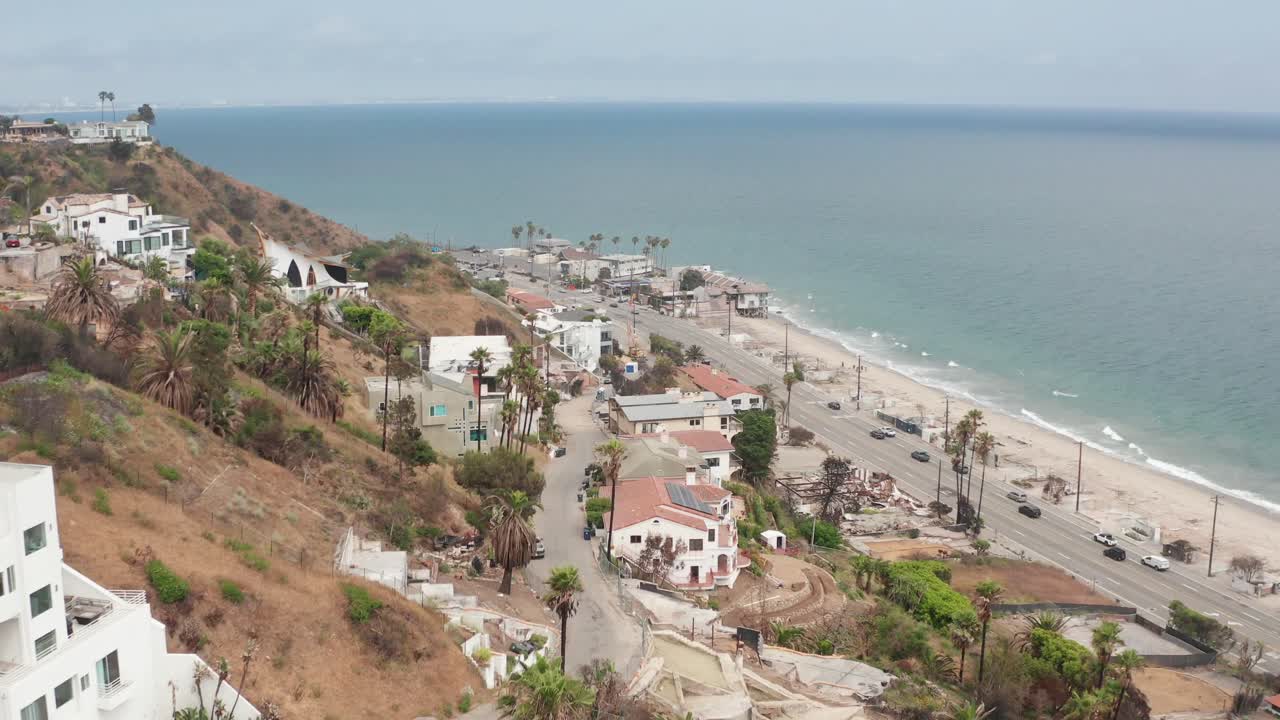 Low aerial shot flying over burned properties on the hillside along Pacific Coast Highway at Las Flores Canyon after the Palisades Fire in Malibu, California. 4K
