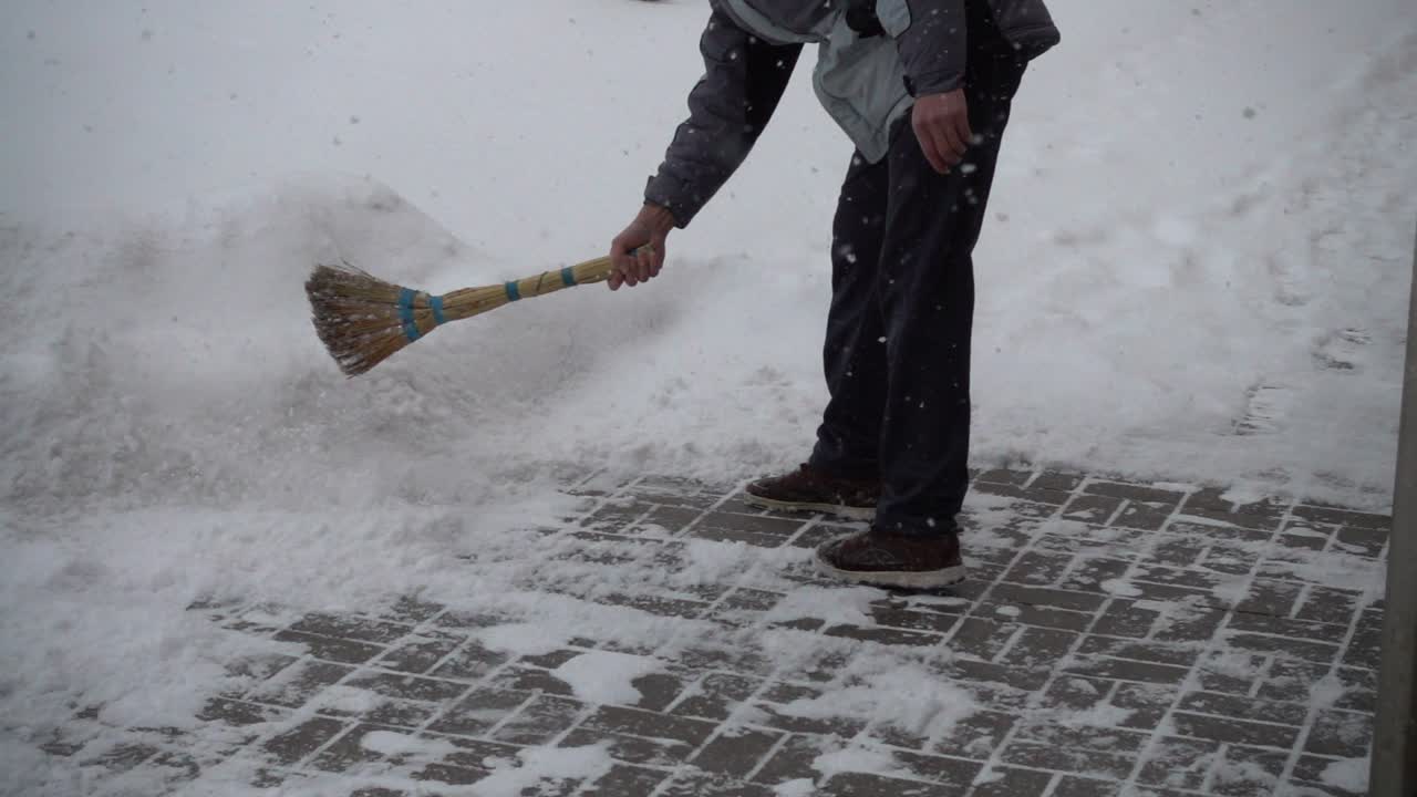 The unknown man cleans the street from snow. Slow motion