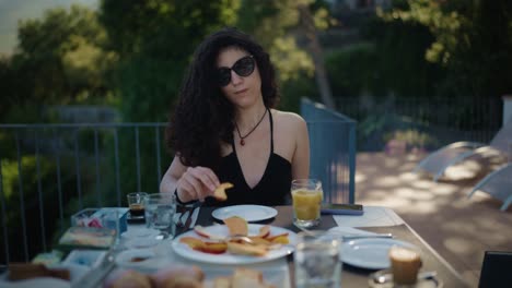 italian woman with curly hair having breakfast outdoors south of italy eating peach